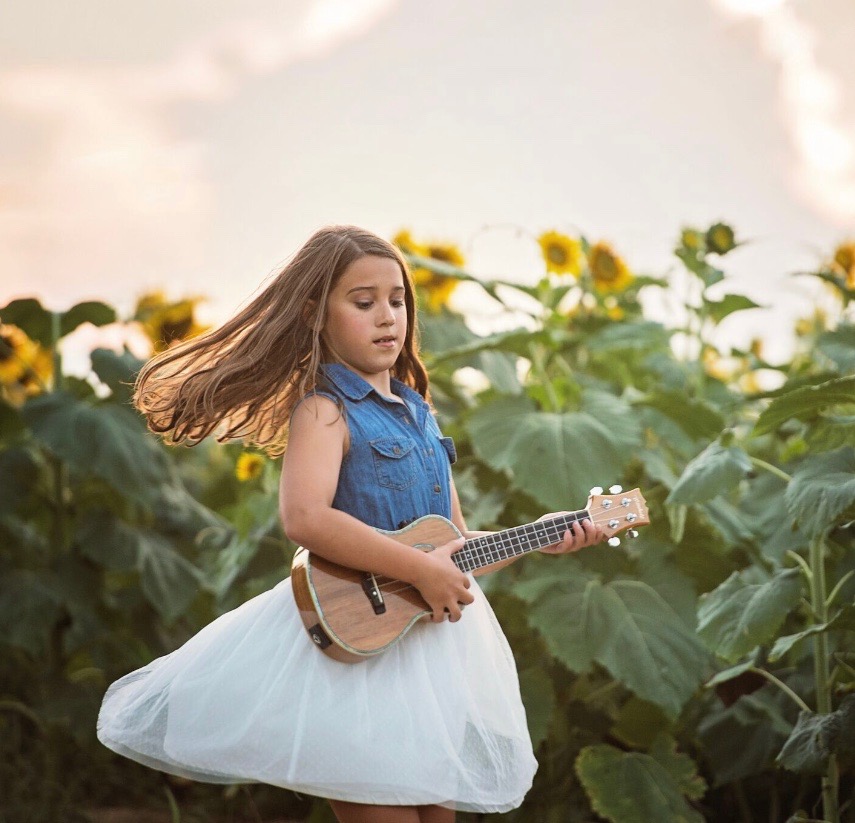 Lulu in a sunflower field with her ukulele