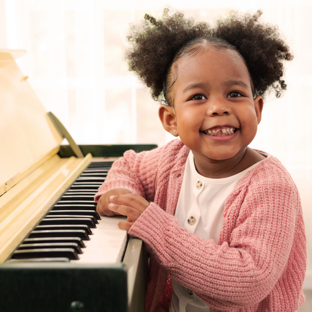Student smiles at the camera while resting her hands on the keyboard
